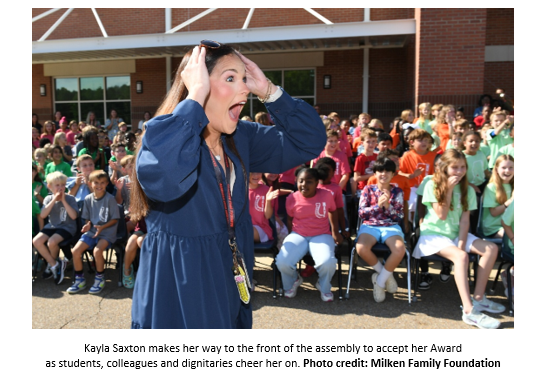 Kayla Saxton makes her way to the front of the assembly to accept her Award
as students, colleagues and dignitaries cheer her on. Photo credit: Milken Family Foundation